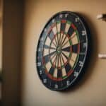 A dartboard hanging on a wall with a set of darts in a well-lit room