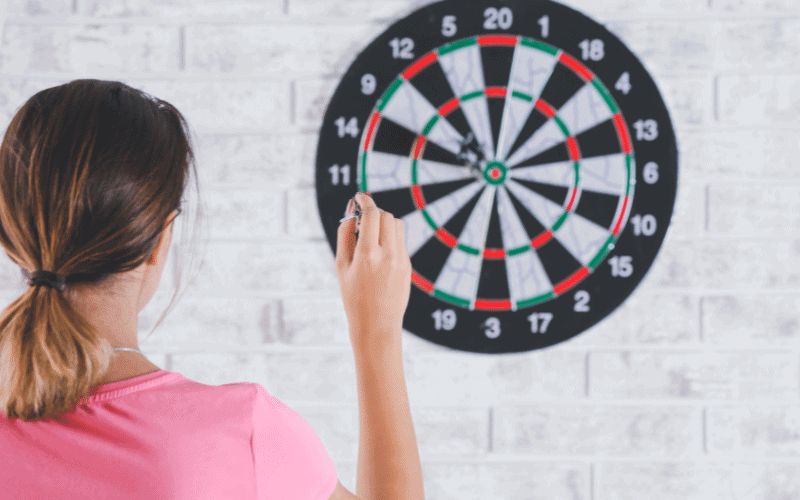 A dartboard with precision darts hitting the bullseye, surrounded by cheering fans and a female player celebrating her victory